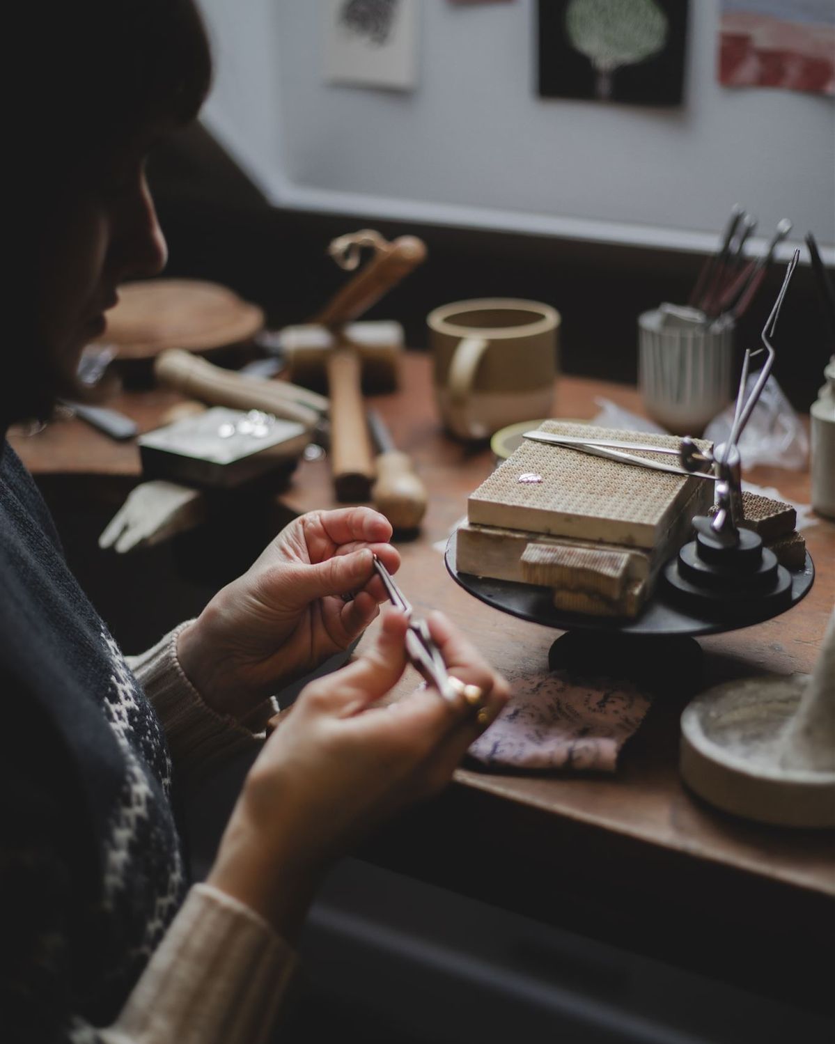 A jewelry maker shaping a piece by hand at a studio workbench